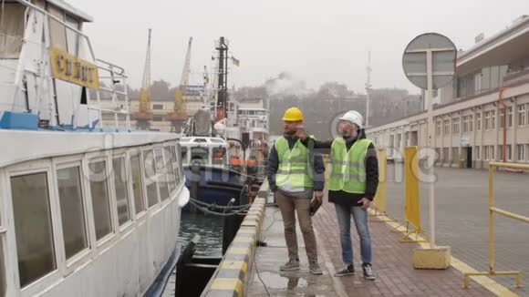 港口工人戴着头盔在船附近谈话视频的预览图