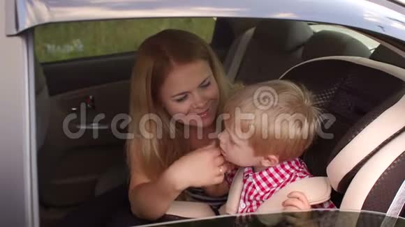 妈妈带着儿子在车上男孩正系着安全带在汽车座椅上视频的预览图