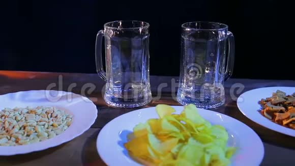 两个透明的啤酒杯放在木桌上背景是黑色的视频的预览图