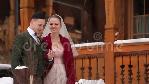 年轻的新婚夫妇走着微笑着说话着手牵着楼梯在滑雪胜地的村庄里有着木制的小屋视频的预览图