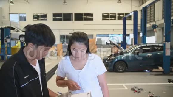 男车技师与客户就汽车修理预算成本和保险进行交谈亚洲女人倾听视频的预览图