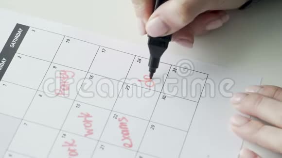 女人用红毛毡笔在日历上写字日期视频的预览图