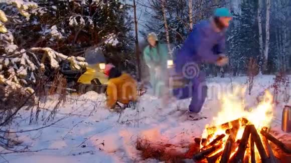 冬季森林一个年轻的家庭在火边的树林里打雪球玩得开心视频的预览图
