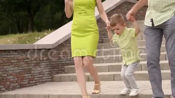 爸爸妈妈和他们的小儿子在公园里走下楼梯视频的预览图