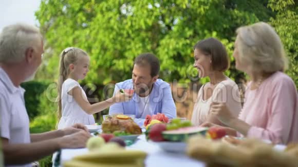 女儿给父亲吃西瓜一家人在吃晚饭的时候玩得很开心视频的预览图