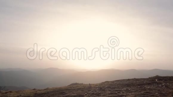 女人在夕阳的天空和山的背景上跳跃视频的预览图