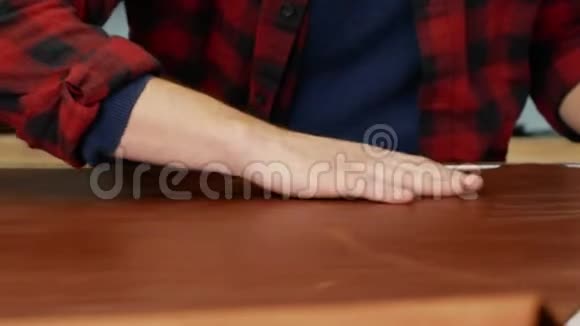 一个剥皮者摸着桌子上的一大块皮革男性皮革工匠检查皮肤是否有缺陷测定视频的预览图