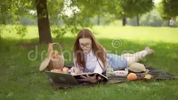 漂亮的年轻女人在美好的一天在草地上看书视频的预览图