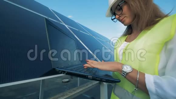一位女士站在太阳能电池板附近对着镜头微笑并关闭视频的预览图