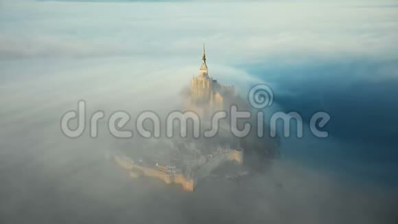 在诺曼底被大气的日出薄雾覆盖的蒙圣米歇尔岛城堡附近无人机飞行得非常近视频的预览图