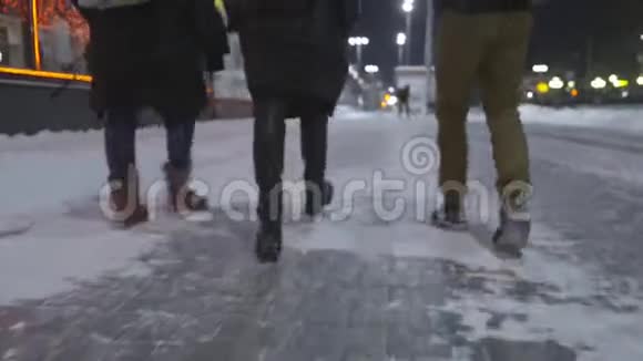 朋友们在冬天的夜晚在城市里走来走去行动三个脚穿靴子的朋友在城里散步视频的预览图