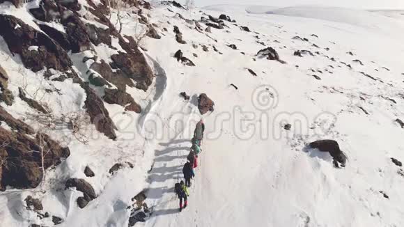 七位旅行者排成一队到达一座覆盖着雪的山顶这有助于他们的装备和背包视频的预览图