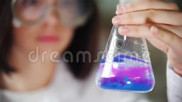 化学实验室的年轻女子拿着一瓶液体摇了摇液体变色把注意力集中在烧瓶上视频的预览图