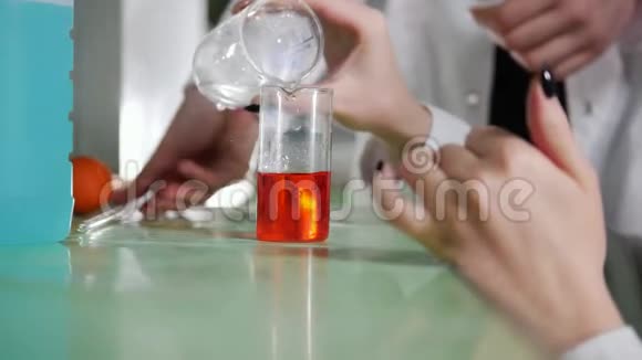 化学实验室年轻女子做实验混合液体寻找反应视频的预览图