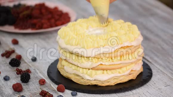 女糕点厨师使用管道袋和旋转蛋糕架装饰蛋糕与奶油霜站在桌子上视频的预览图