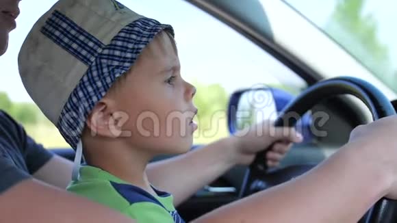 那个男孩坐在车里他坐在爸爸怀里抱着方向盘乡村道路视频的预览图