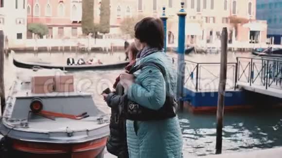 两位快乐的高加索人老太太一起沿着运河大桥散步欣赏意大利威尼斯的退休假期视频的预览图