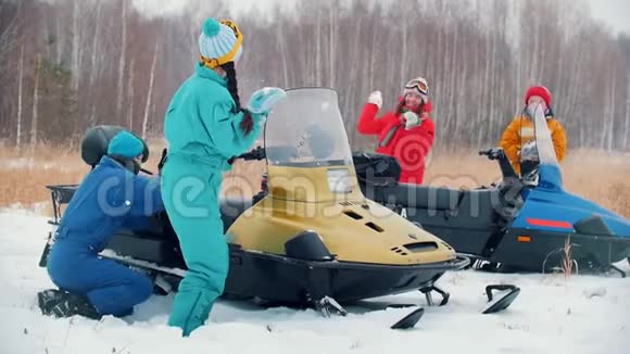 冬季森林一个玩雪球的年轻家庭躲在雪地摩托后面慢动作视频的预览图