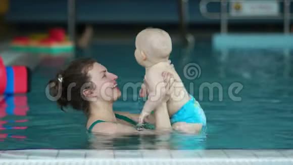 一个女人在一个室内游泳池里扔出一个一岁的饱婴儿孩子开心地笑了妈妈健康的一天视频的预览图