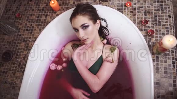 美丽温柔的年轻女子在水疗沙龙里用玫瑰放松洗澡可爱的女孩在浴室里享受视频的预览图