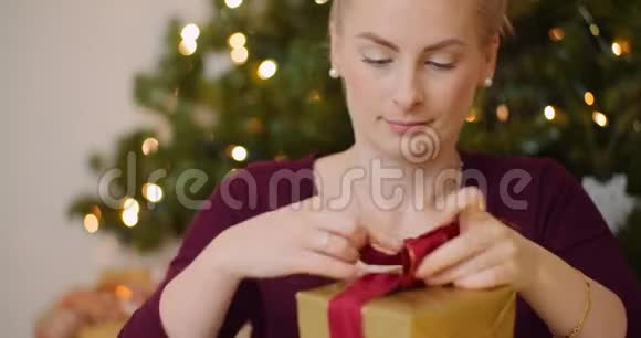 有魅力的女人在家里的礼品盒上系丝带视频的预览图