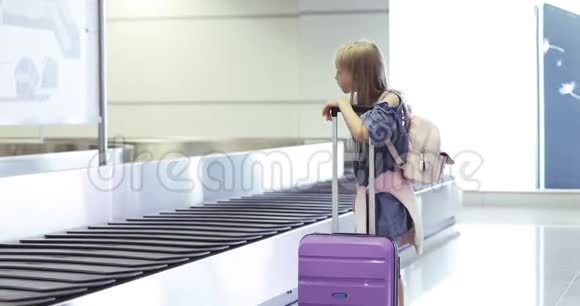 一个可爱的小女孩从行李托运箱里拿出一个紫色的手提箱视频的预览图