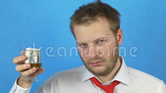 一个留着胡子的年轻人穿着白色衬衫和领带手里拿着一杯酒里面有钱特写视频的预览图