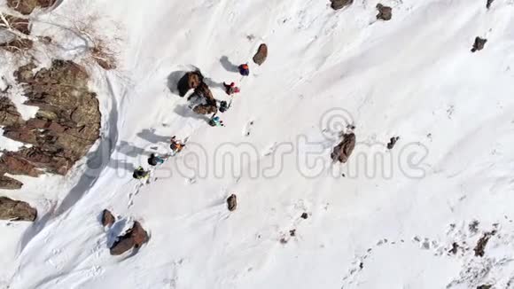 一群游客在同一条小径上在石头和雪堆之间空中互相跟随视频的预览图