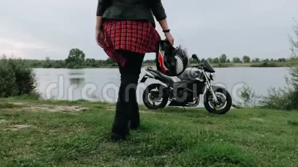 一个年轻的女孩走近她的摩托车它站在湖岸上4K慢动作视频的预览图