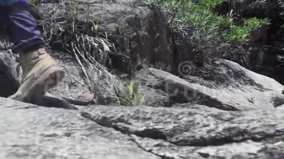 从山上的瀑布流下的河水中男人踩在石头上男足穿鞋在落基山漫步视频的预览图