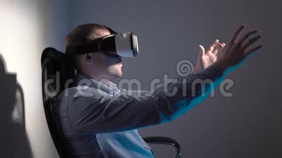 一个戴着虚拟现实耳机的年轻人坐在烟雾弥漫的房间中间的椅子上挥动着他的双手视频的预览图