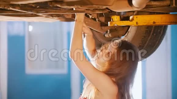 机械师女孩在车下带着扳手把她的头拉到一边视频的预览图