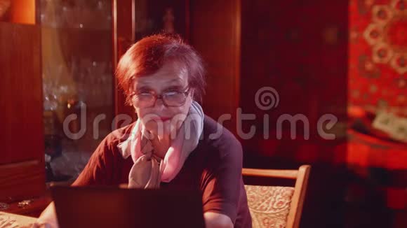 漂亮的老太太坐在笔记本电脑和上网显示器前微笑视频的预览图