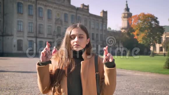 美丽的白种人女人站在那里她的手指交叉着展示着她对城市背景的渴望视频的预览图