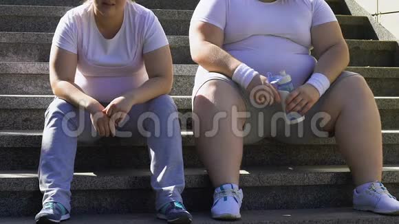 胖乎乎的男人和女人在楼梯上辛苦锻炼后休息呼吸急促视频的预览图