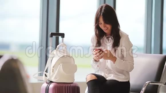 航空公司乘客在机场休息室等待航班飞机白种人女人在候诊室用手机说话视频的预览图