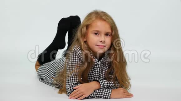 一个穿着格子连衣裙的女孩躺在地上轻轻地对着镜头微笑视频的预览图