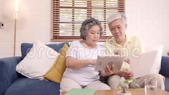 亚洲老年夫妇在家客厅里用平板电脑看电视视频的预览图