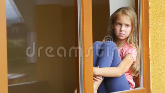 一个害羞的女孩坐在窗前看着街道向某人挥手致意视频的预览图