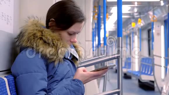 疲惫的女人坐在空的地铁车上浏览她的智能手机的肖像侧视视频的预览图