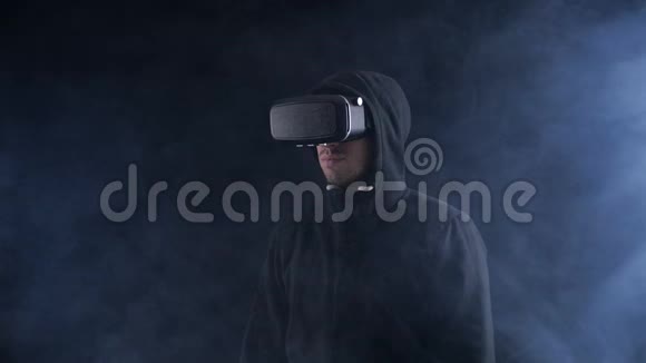 在烟雾弥漫的黑暗地方戴vr眼镜或虚拟耳机的年轻人新技术增强现实视频的预览图