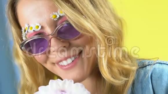 迷人的女人带着白色的花朵微笑着摆成相机化妆品视频的预览图