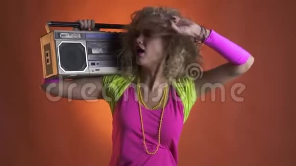 80年代的女孩穿着五颜六色的服装肩上扛着一个吊臂箱欣赏音乐视频的预览图