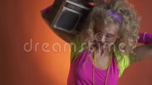 复古的金发女人在她肩上的吊杆盒里摇着头听音乐视频的预览图