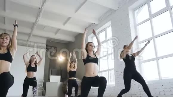 年轻有魅力的女性在健美操课上做热身运动健身女孩进行步冲运动体育和健康视频的预览图
