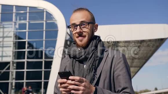 一位戴眼镜的年轻商人用现代智能手机在城市街道上行走这一切都发生在一个视频的预览图