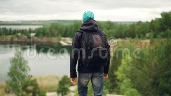 背着背包的年轻旅行家慢步下山观景写真视频的预览图