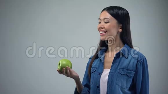 漂亮的女人在灰色背景的医疗保健上摆着多汁的苹果视频的预览图