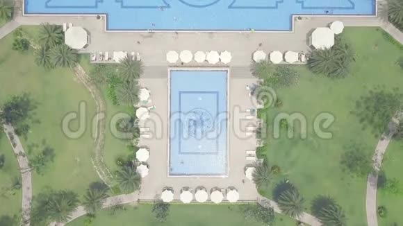 蓝色游泳池雨伞和绿色草坪在豪华度假酒店鸟瞰酒店和桑迪大型游泳池视频的预览图