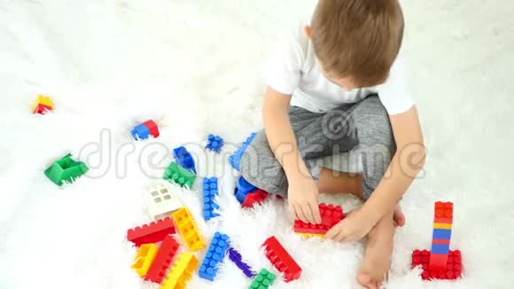 一个孩子在白色背景上玩彩色积木儿童发展的概念从上面看视频的预览图